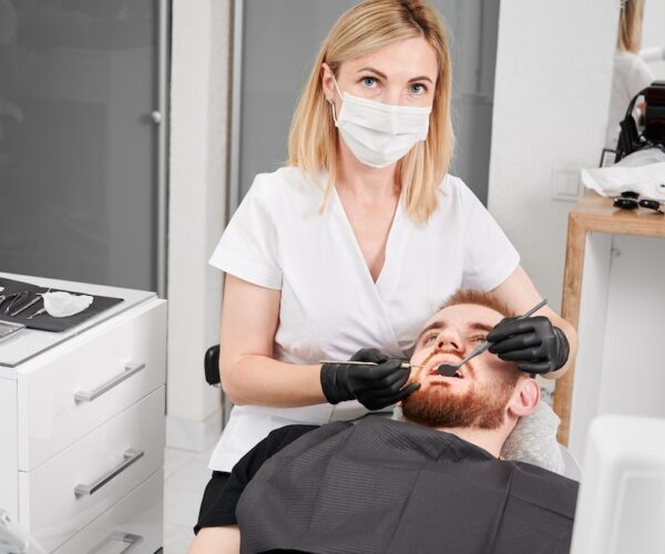 Woman stomatologist in medical mask looking at camera while examining male patient teeth with dental explorer and mirror. Concept of dentistry, stomatology and dental care. SSUCv3H4sIAAAAAAAACnRTy24dIQzdV+o/XLEOKvNm8gXdRO2+6sKAJ5eGO1wBkyqK8u8187ilVbJB+Ng+x8bm9fOn04kpiFaz+9Nrtsi2zi0xBUjWzwSLux0POBsMJfIcml6UABqbfLDgSlBB0ucZLkjgvDiX4bfVyWKCtESMWX2HNCR8JI4NvFFsJf7Y7NPhWJ2UQS72FcGls4aAXx6oDk1F3BVRcVE56pv6hTpFdng21Q8ov6O/OnyP5sFGjc7BjH4pyLbLz6NzeMRZv/ztI0MOLi9lJ4T9I9DovpcSFJ8GrXmrJ8Fl3yMfq4o8WAs1iZvgoZSJjVcYk9dP/7FXopfNexkmIFxisutgPqynognfkrfL2uY+roAOYZvgTsEGWY+VMA1vp3zopucwoOBg2rEbBUiCDwkGatCtrAUfaq14a8zEpWo7bugJEAcY5ShX/a1w9vQ7YbiUCwOLsb7YlWdPo88BTVHmNVht58cizafzusxHmvbLnEIeza1/5ry/gqINuD9NxIkHfoYYKdwceCGk6ev4S6Ez+7S+zs7KDO13Nqum7oaxbfpOjnXfNqLeA7Y/cbbEs5ZzEK2ztaZs3eYKGAyNaEaceNuPkg7ouNJDXhtd61q2ncGKnvDtDwAAAP//AwDFAvD27gMAAA==
